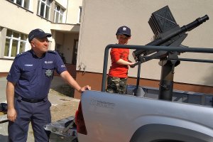 Policjant z dzieckiem przy automatycznej wyrzutni granatów łzawiących.