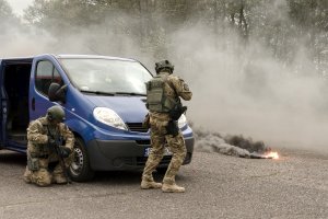 Dwóch policjantów przy samochodzie dostawczym, w tle zadymiona droga.