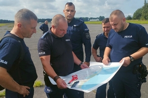 Policjanci trzymają w ręku mapę sztabową.