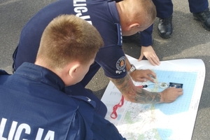 Dwóch policjantów pochyla się nad mapą sztabową.