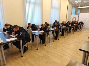 Policjanci siedzący przy biurkach rozwiązujący test