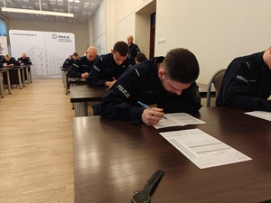Policjanci siedzący przy biurkach rozwiązujący test