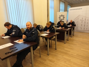 Policjanci siedzący przy biurkach rozwiązujący test