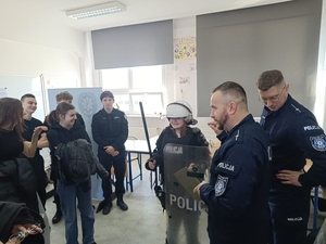 policjanci ubierający uczniów w sprzęt przeciwuderzeniowy