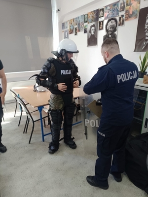 policjanci ubierający uczniów w sprzęt przeciwuderzeniowy
