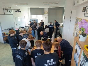 grupa uczniów z policjantami w sali lekcyjnej