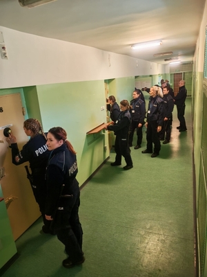 policjanci na korytarzu pomieszczenia dla osób zatrzymanych