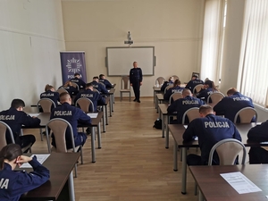 policjanci siedzący w ławkach i rozwiązujący test